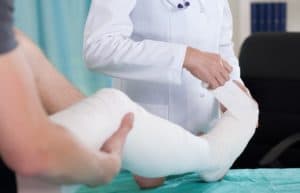 Doctor changing plaster to patient with leg injury due to accident.