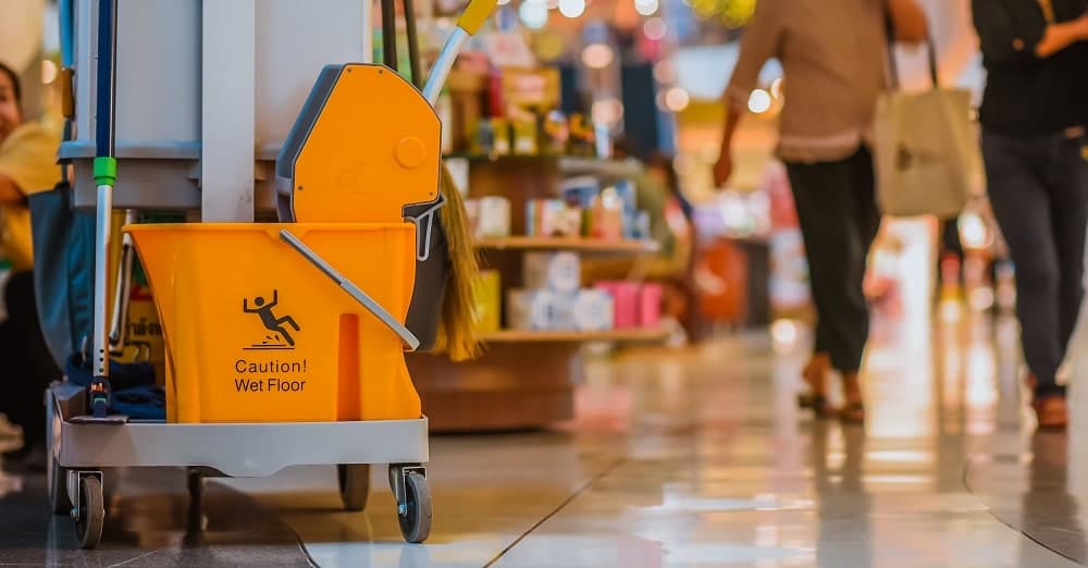 Yellow mop bucket floor cleaning equipment and mops in shopping mall.