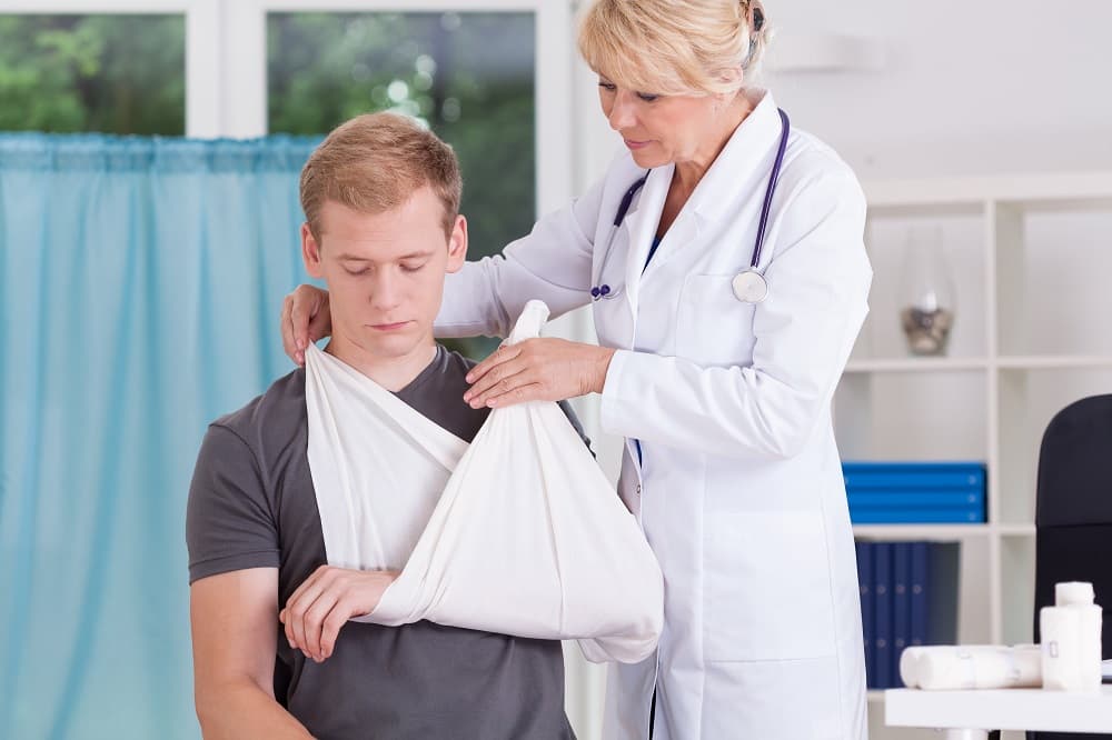 Doctor putting bandage to patient's injured arm.