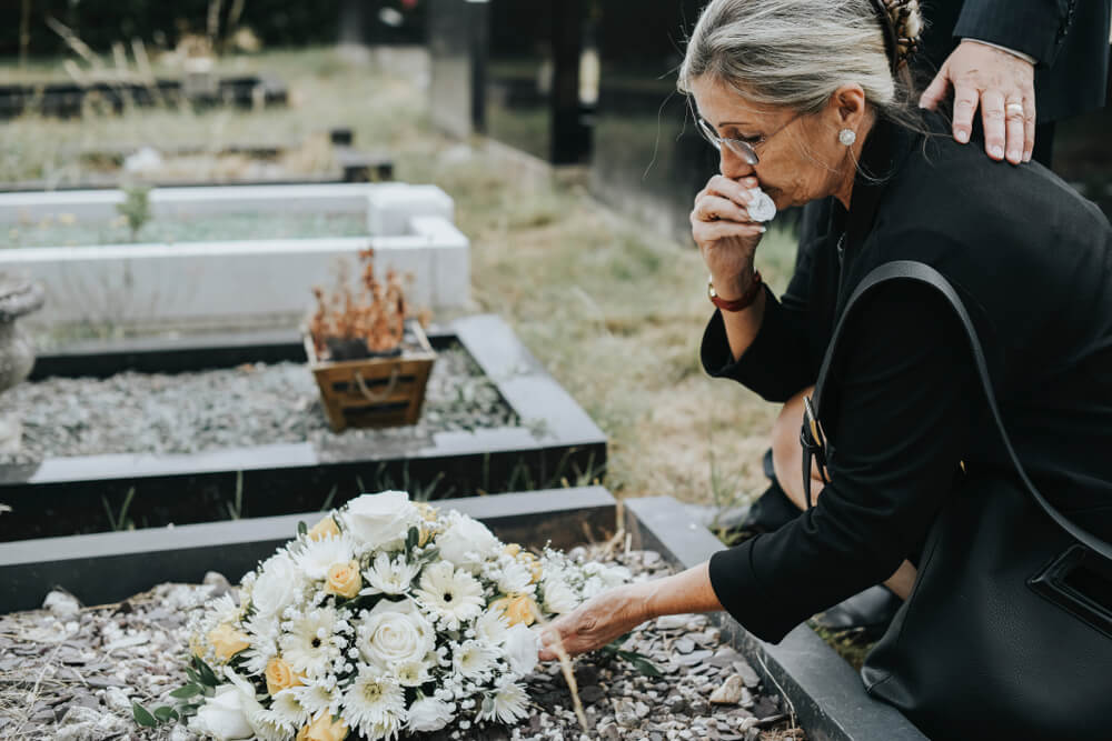 Grieving mother offering flowers in the cemetery.