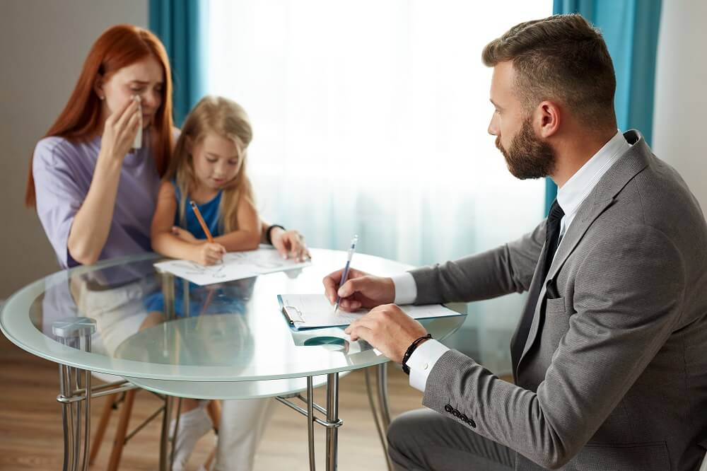 Crying mother with child consulting lawyer over husbands death.