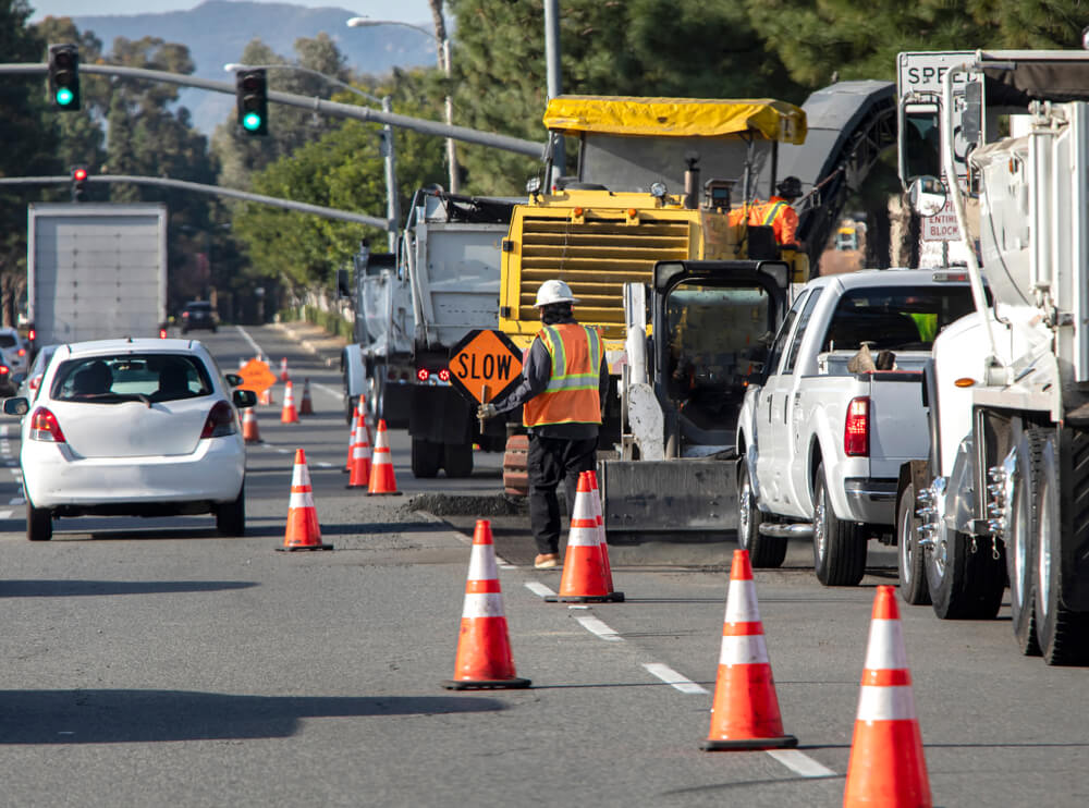 Road construction site and a man holding traffic sign that says SLOW.