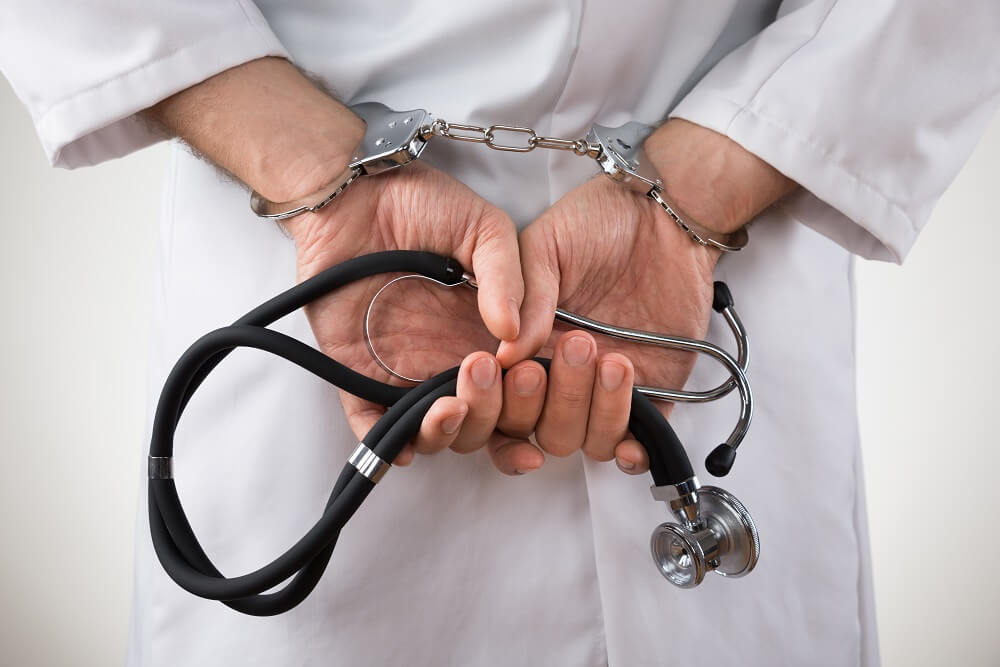 Doctor is handcuff while holding stethoscope.