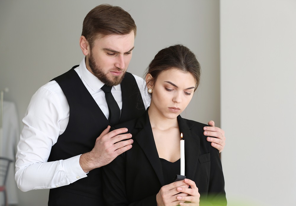 Sad couple offering prayers at a funeral