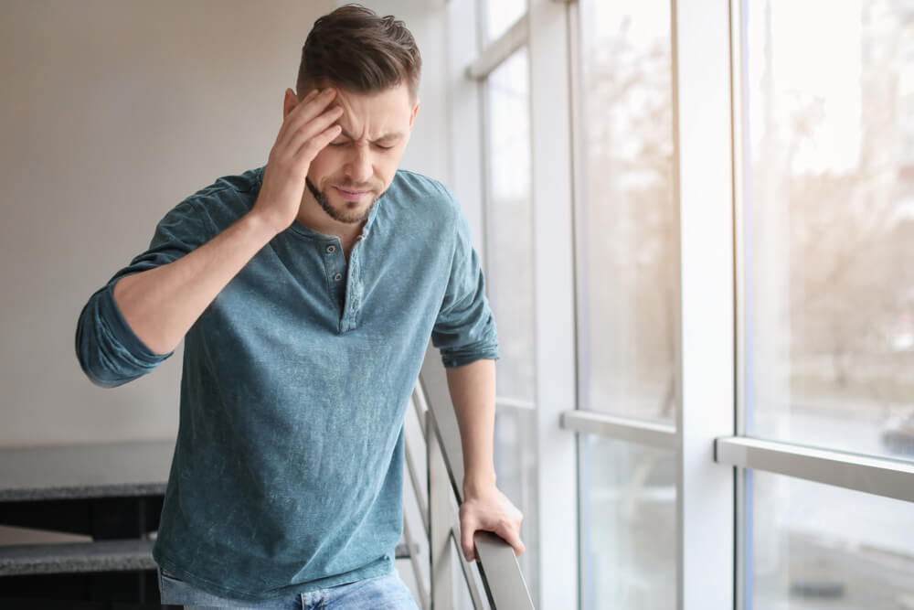 Man suffering from headache near window in office.