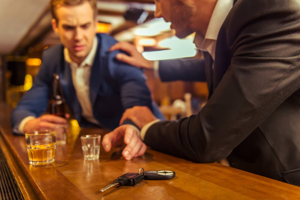 Young drunk driver in the dram shop reaching for his key.