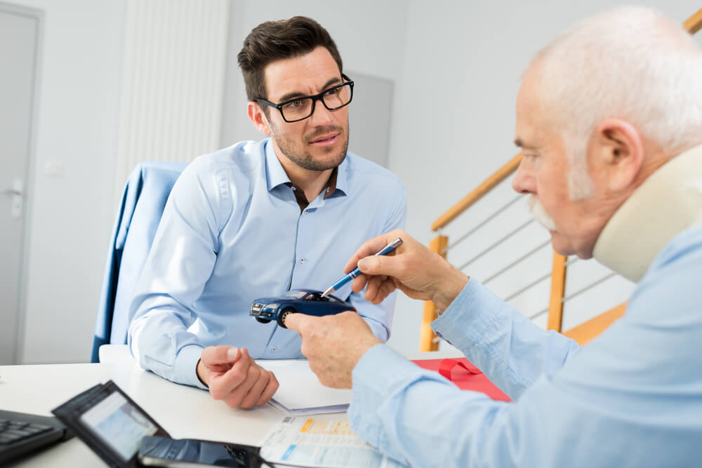 Injured driver talking to insurance adjuster about the car accident for claims.