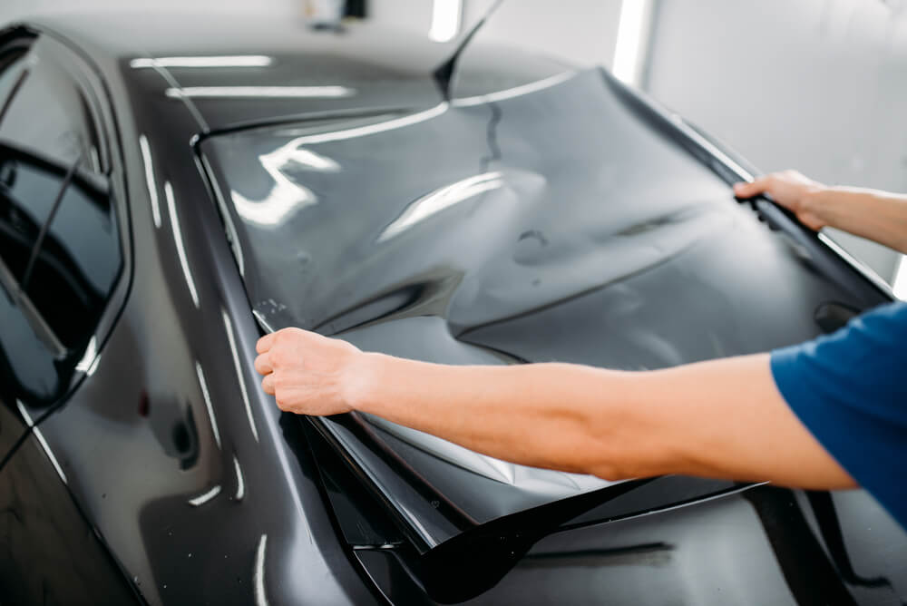 Male specialist with car tinting film in hands.