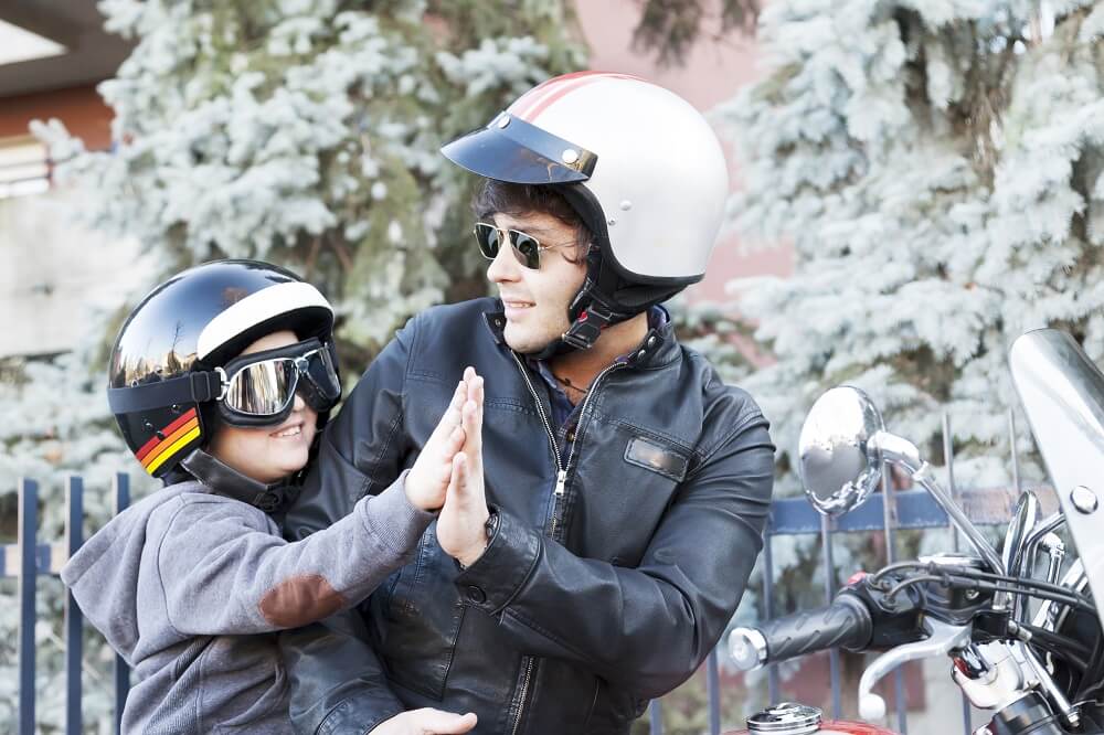 Father and son tandem wearing safety gears for motorcycle ride.