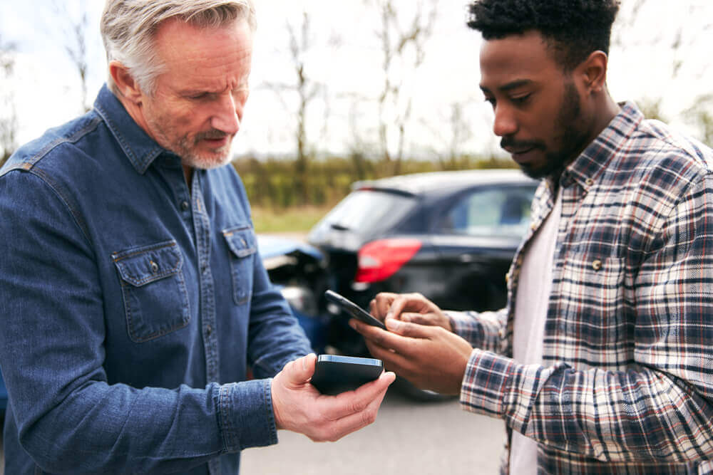 Drivers in car accident exchanging their contact details.