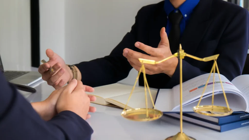 Two lawyers in business attire converse about a case, highlighting their teamwork and legal expertise.