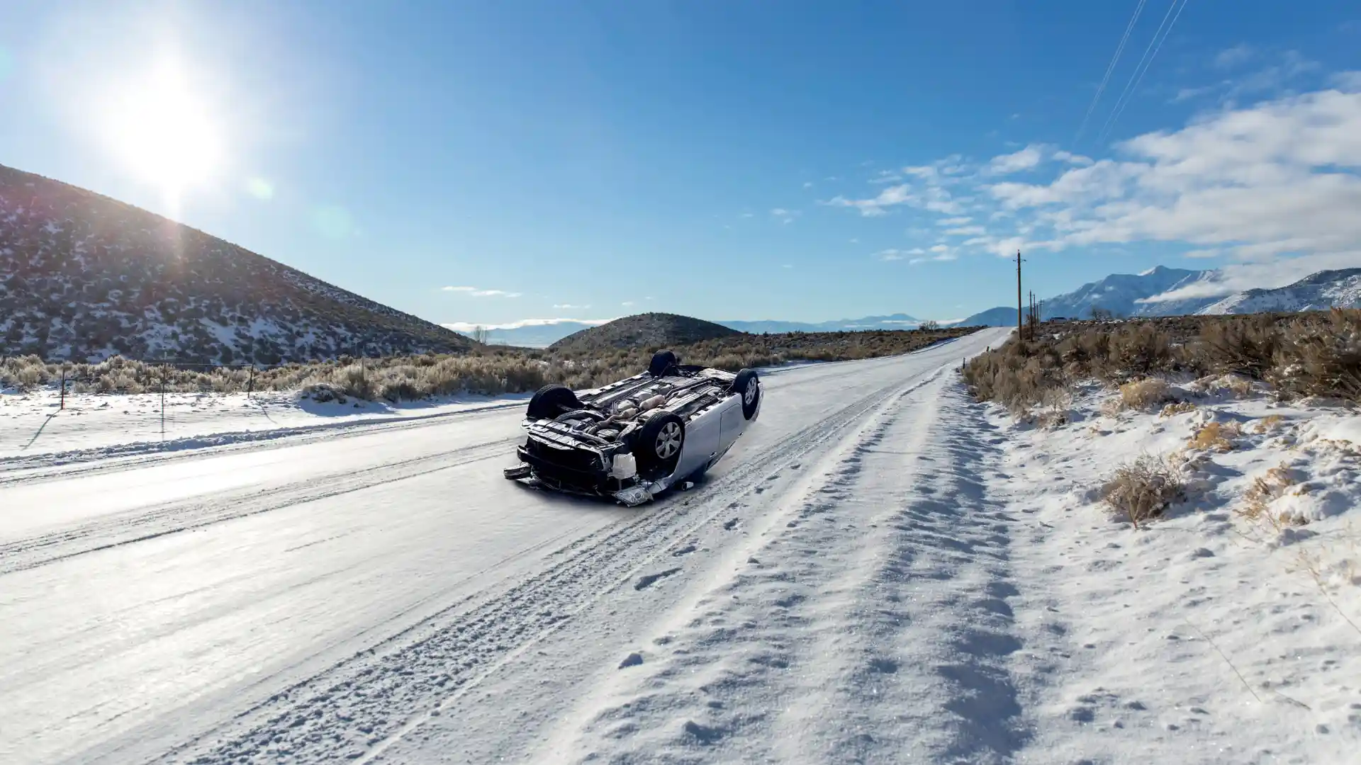 An upside-down car on a snowy road, illustrating a winter accident scenario.
