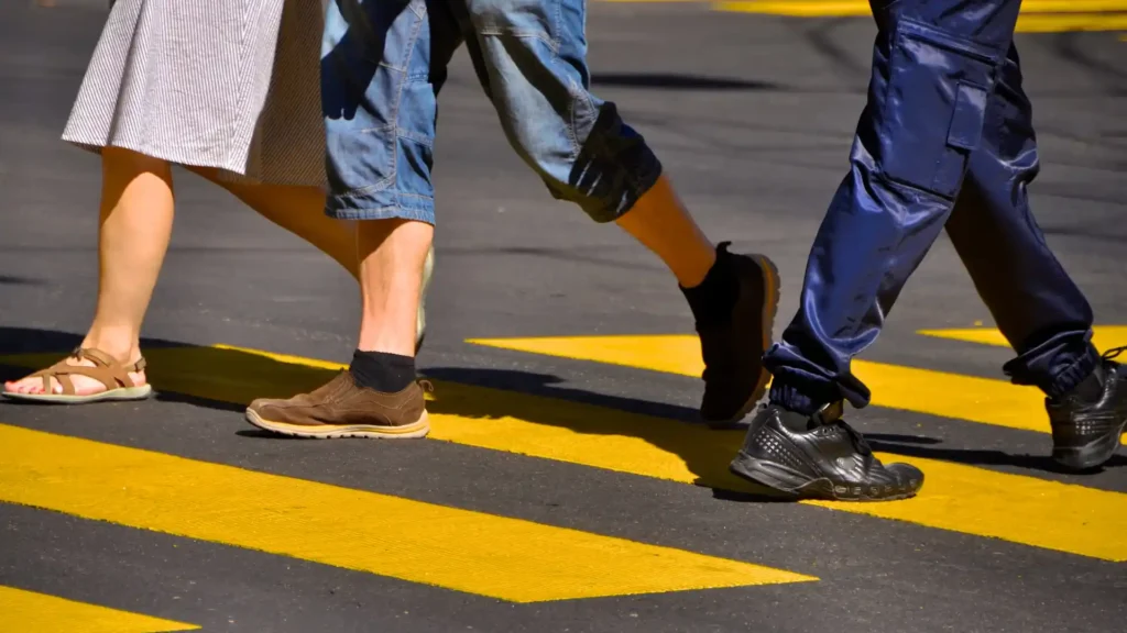 Pedestrians walking across a yellow-striped crosswalk