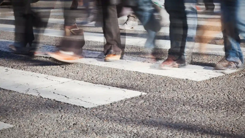 Blurred pedestrians crossing a white-striped crosswalk