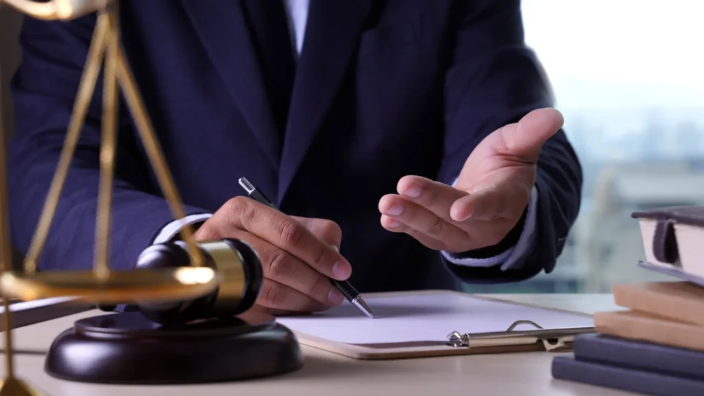 Lawyer writing with a gavel beside a notepad.