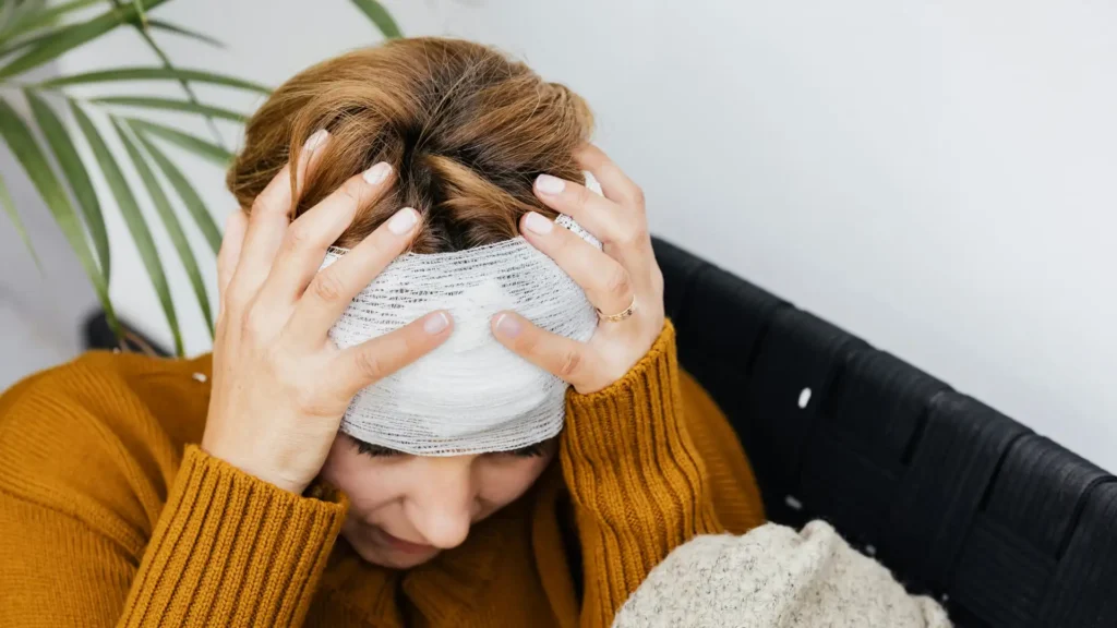 Injured woman holding her head with a bandage