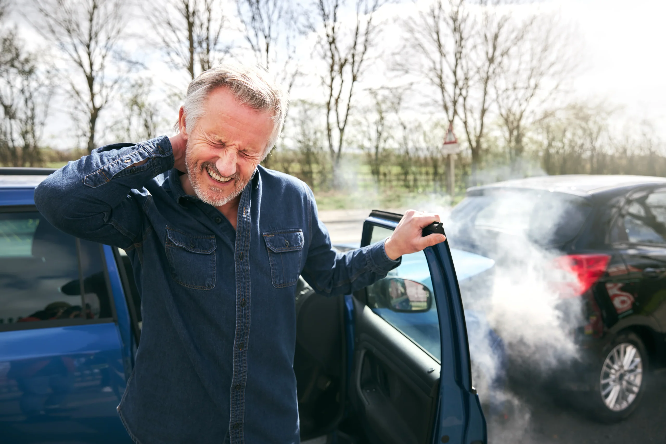 man holding his neck in pain after a car accident with property damage